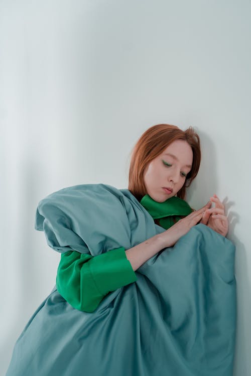 A Woman with Green Blanket Leaning on the Wall