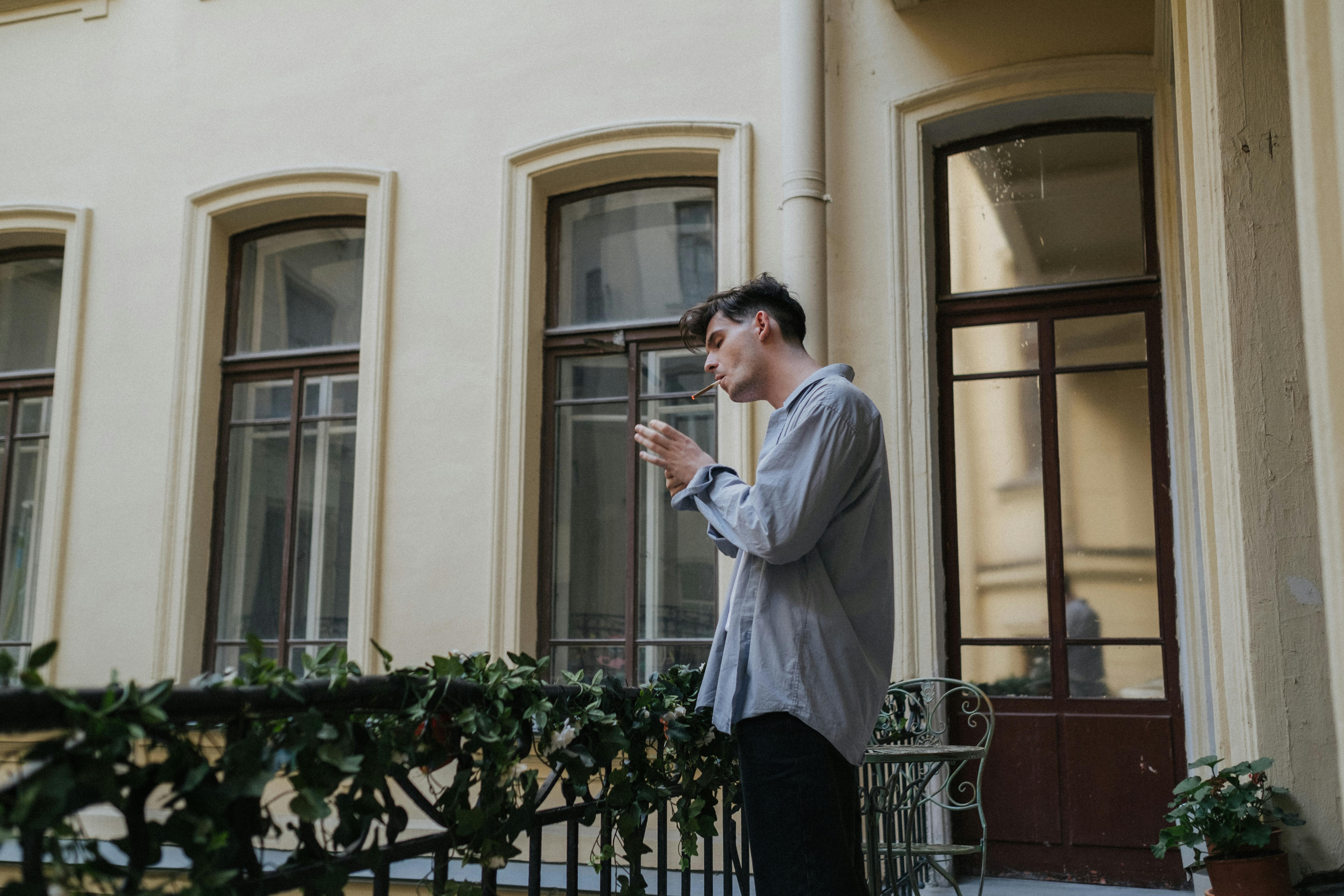 man in white dress shirt and black pants standing near white concrete building