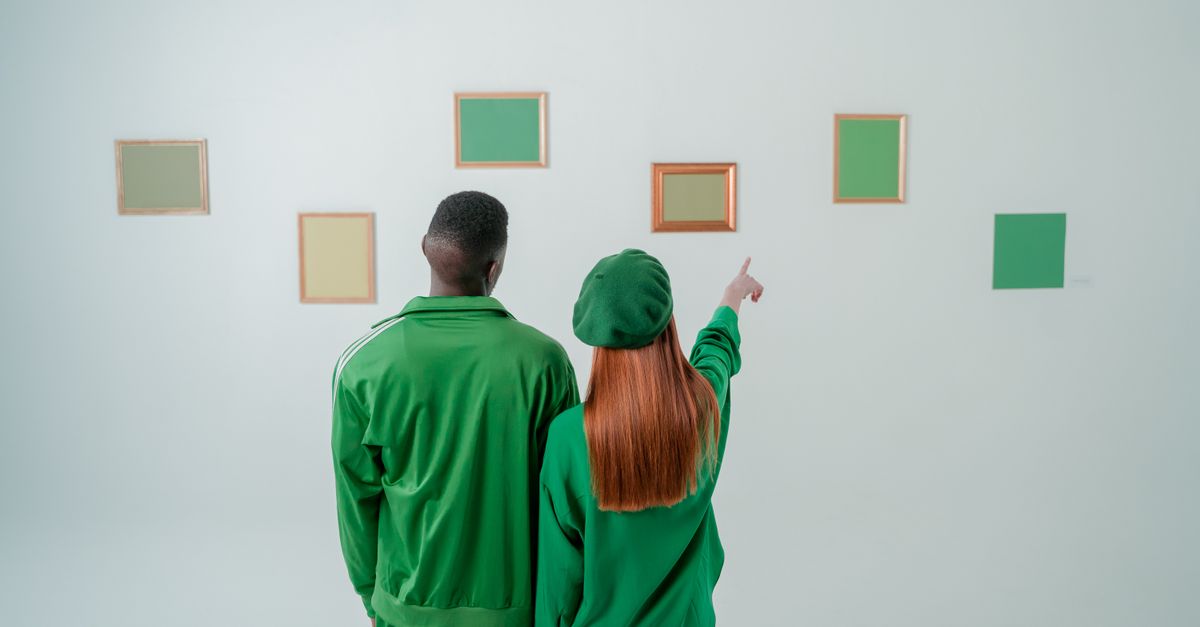 A couple exploring a minimalist art gallery with green-themed frames on the wall.