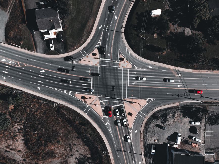 A drone's eye view of a busy city intersection with multiple cars in motion.