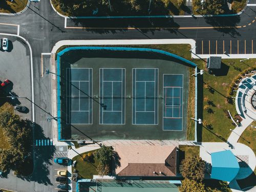 Free Aerial view showcasing tennis courts next to roads and parked cars in an urban setting. Stock Photo