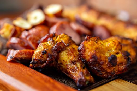 Close-up of a delicious roasted chicken and sausage meal on a wooden platter.