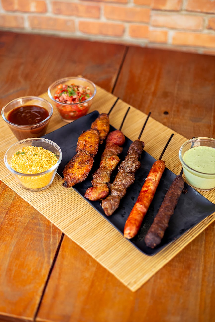 A variety of grilled skewered meats served with sauces and side dishes, perfect for a traditional meal.