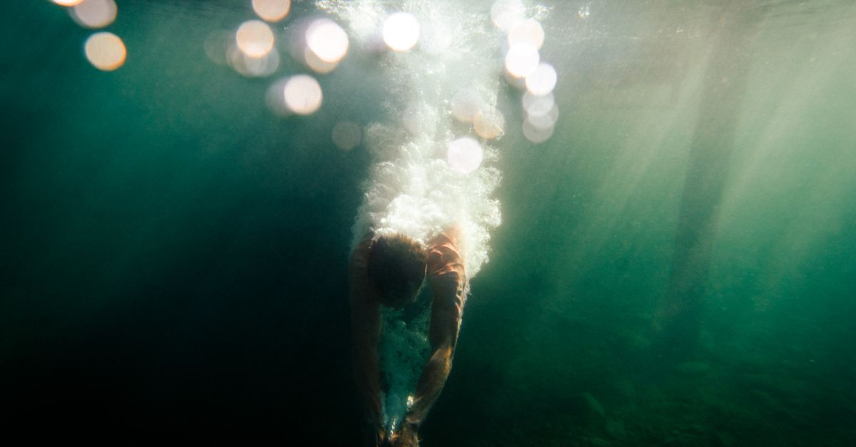 Dynamic underwater shot capturing a diver in motion with a splash, set in vibrant blue waters.