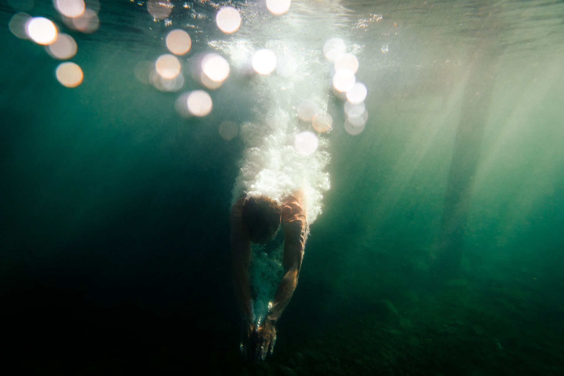 Dynamic underwater shot capturing a diver in motion with a splash, set in vibrant blue waters.