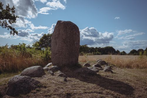 Free Explore this rune stone in a serene field under a partly cloudy sky, evoking a sense of ancient mystery. Stock Photo