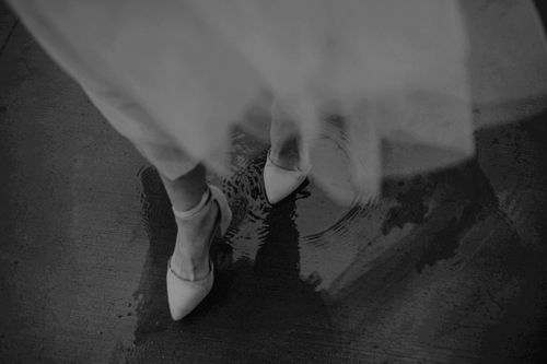 Free A black and white image of elegant stilettos creating ripples in a puddle, taken with a Canon EOS 5D Mark IV. Stock Photo