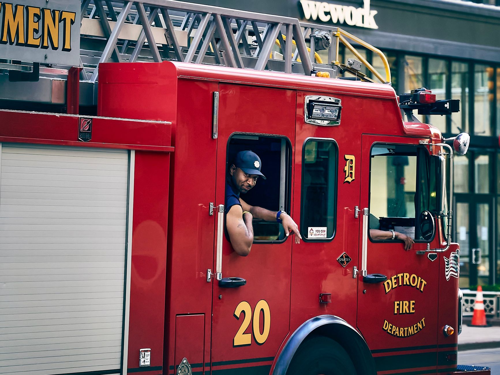Firefighter operating Detroit fire engine in urban setting.