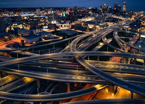 A night aerial view of Milwaukee's illuminated cityscape featuring intricate highway interchanges.