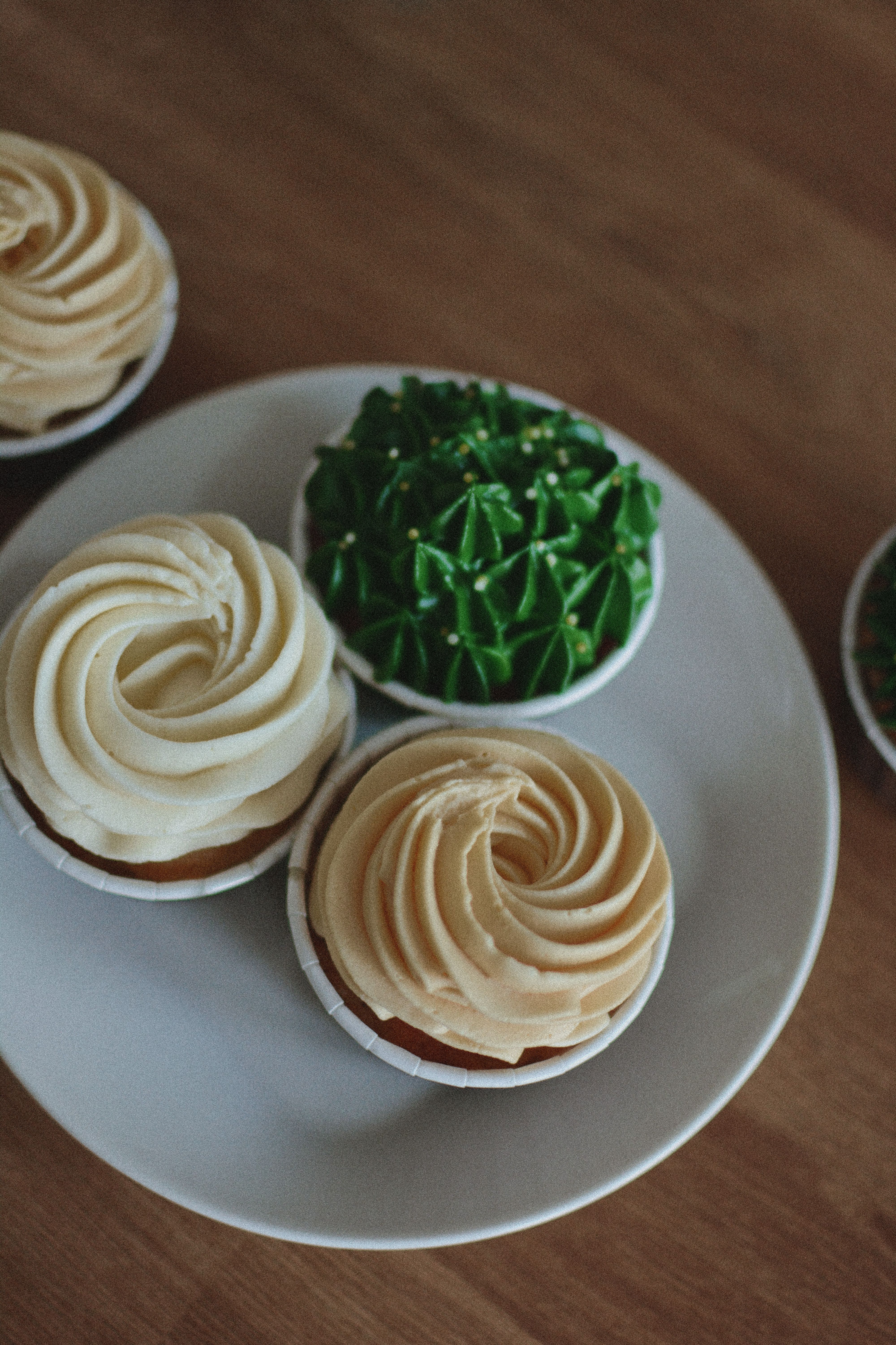 Close-up of assorted decorated cupcakes on a white plate.
