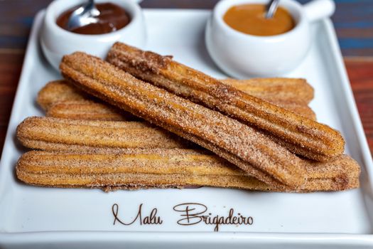 Close-up of churros with cinnamon sugar and chocolate, caramel dips.