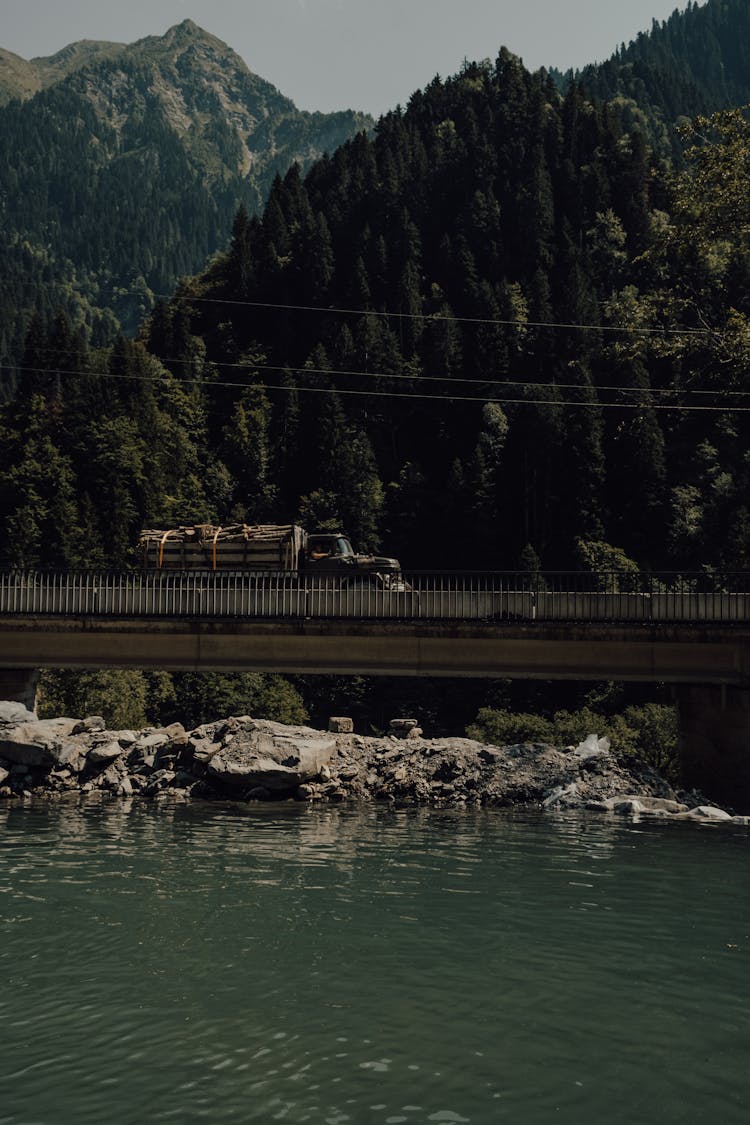 A Truck With Firewood Passing A Bridge