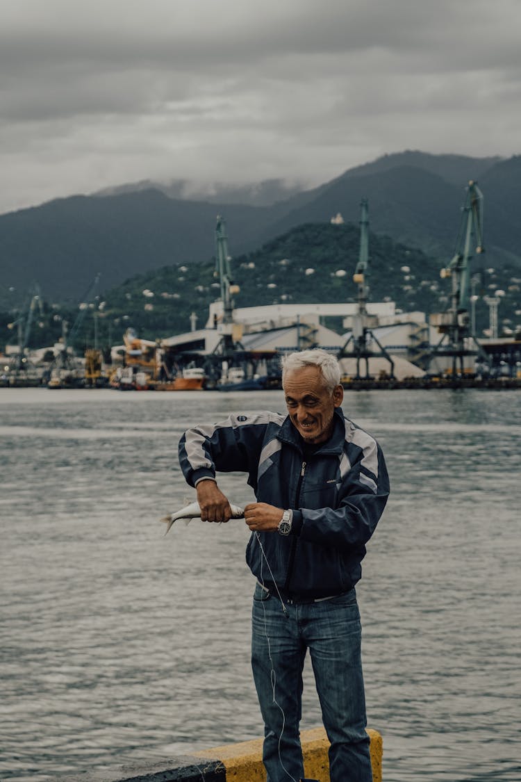 Man Removing A Catch Fish From Fishing Line