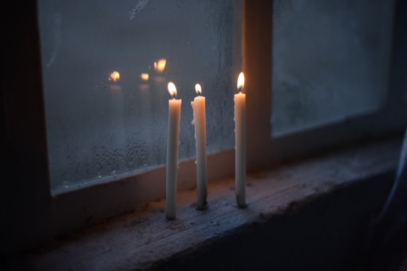 Slim lit candles standing on a quiet windowsill