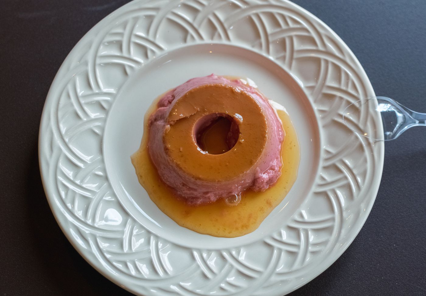 Top view of a delicious flan dessert served on an intricately designed white plate.