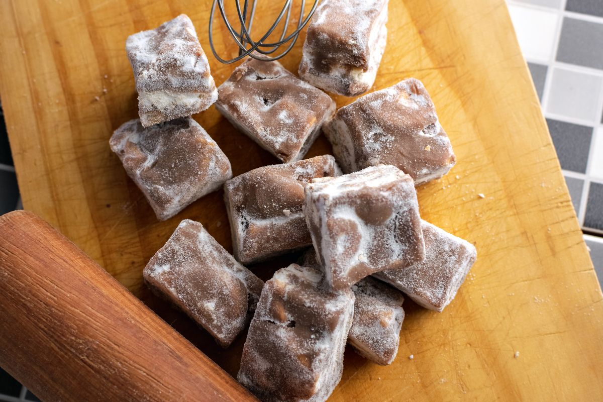 Top view of homemade chocolate candies dusted with powdered sugar on a wooden board.