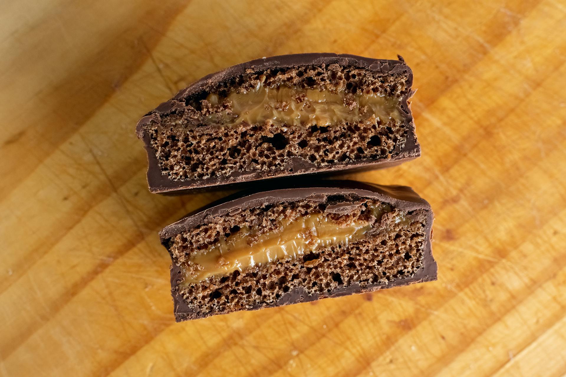 Delicious chocolate cake slice with caramel filling on wooden board.