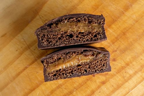 Free Delicious chocolate cake slice with caramel filling on wooden board. Stock Photo