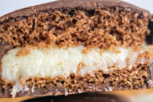 Macro shot of a chocolate-covered cake with creamy filling, showcasing texture and layers.
