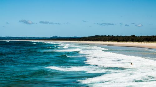 Free Vibrant ocean waves hitting a sandy tropical beach under a clear blue sky, ideal for travel and nature enthusiasts. Stock Photo