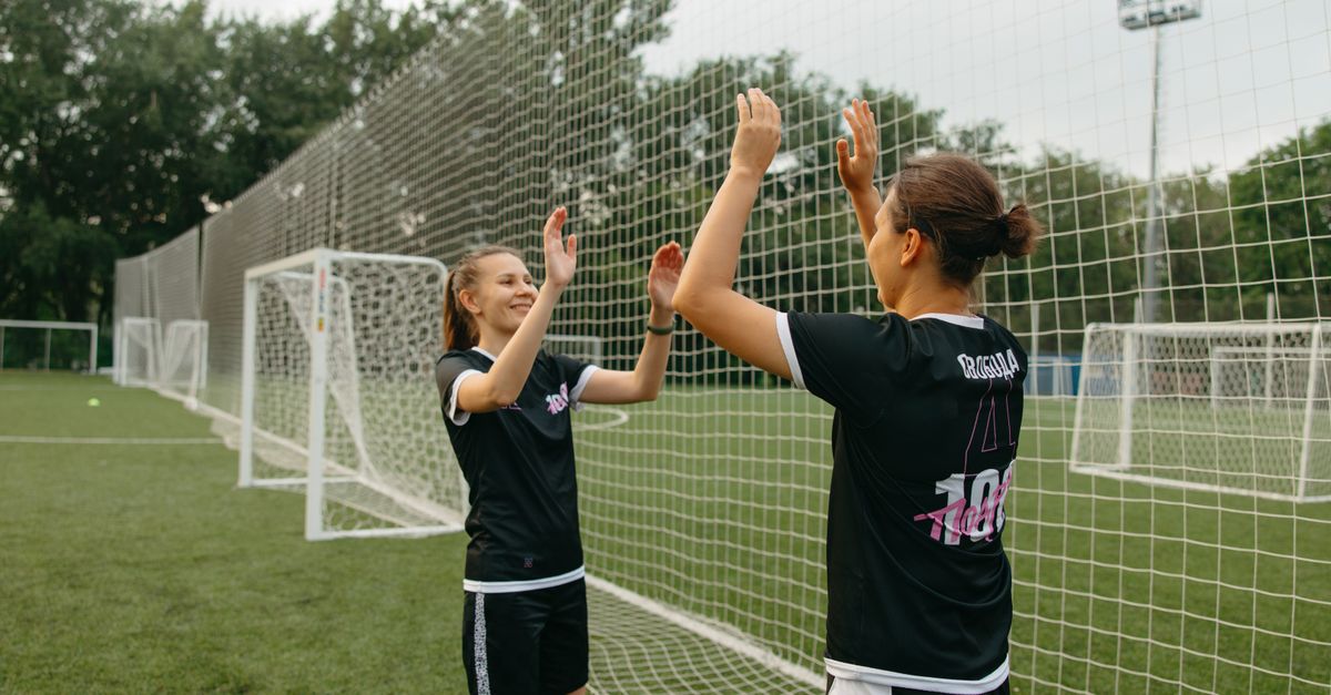 Two athletes from different sports (e.g., basketball and soccer) having an animated conversation on a field