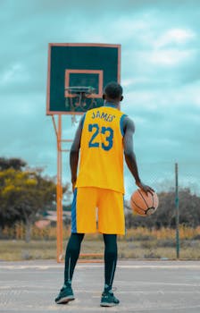African American athlete playing basketball on an outdoor court.