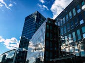 在晴朗的日子里，当代摩天大楼的玻璃外墙反射着天空和云层