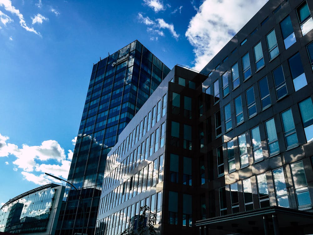 Low-angle Photography of Curtain Wall Building Taken Under White Clouds and Blue Sky