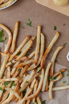 A delicious serving of golden crispy french fries seasoned with salt and herbs, perfect for snacking or sharing.