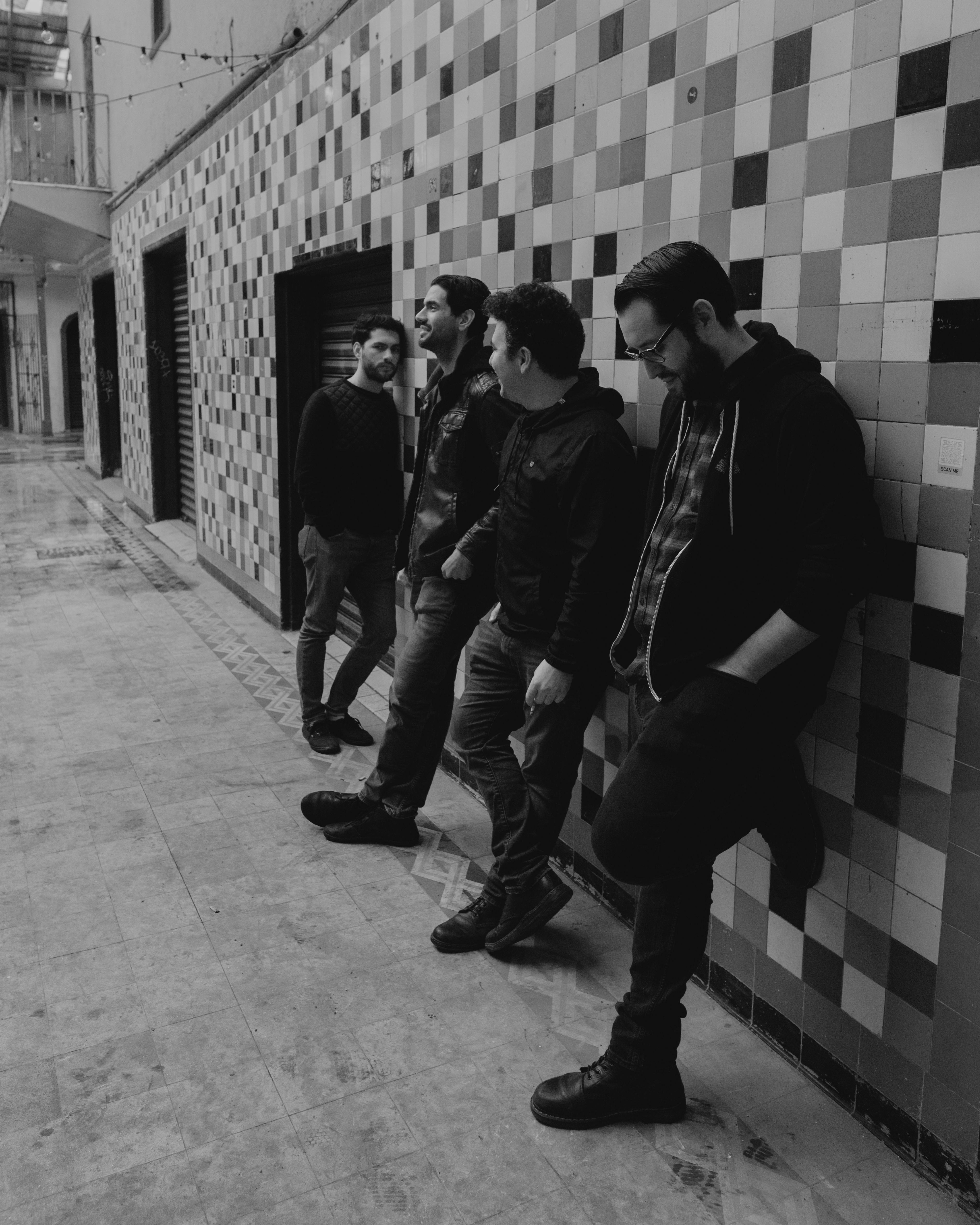 Men in casual attire leaning against a tiled wall, embodying urban subculture in monochrome.