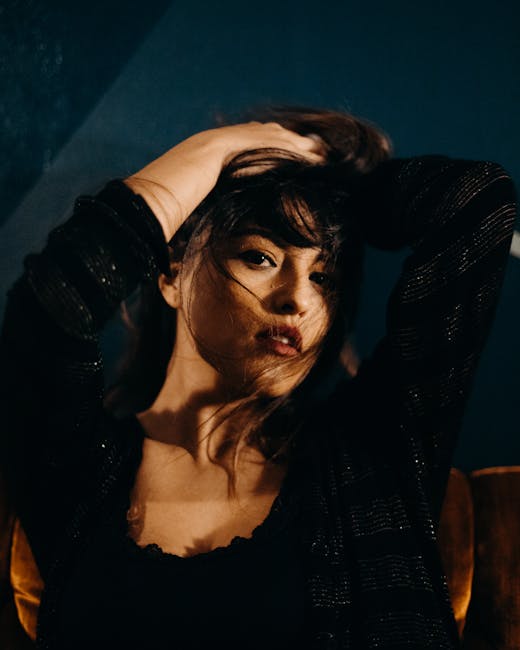 Captivating portrait of a woman with dark hair in moody lighting, striking a pose indoors.