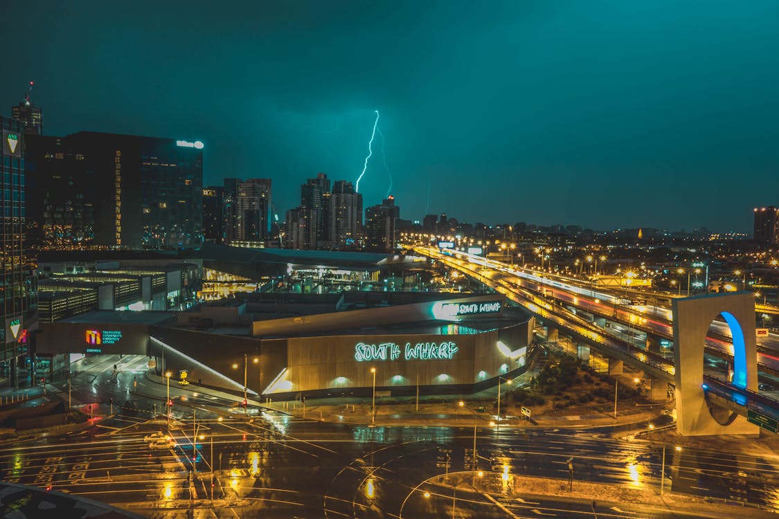 Free Bird's Eye View of Grey Building Near Road and Thunder Lighting Strike in Background Stock Photo