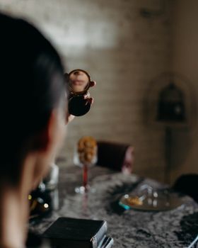 A person holding a small mirror, reflecting their face, indoors.
