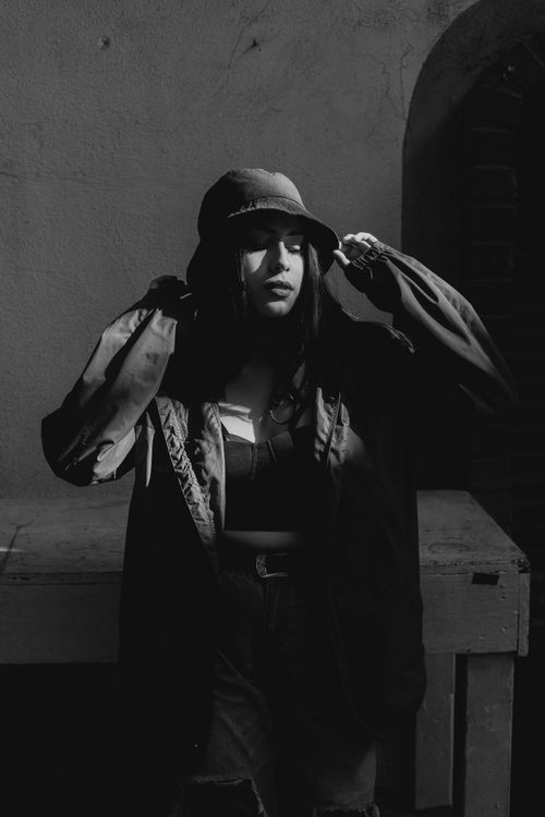 Free Modern black-and-white photo of a stylish woman wearing a bucket hat and jacket in urban setting. Stock Photo
