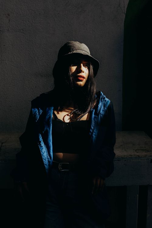 Free Dramatic low-light portrait of a woman in a fashionable outfit with contrasting shadows. Stock Photo