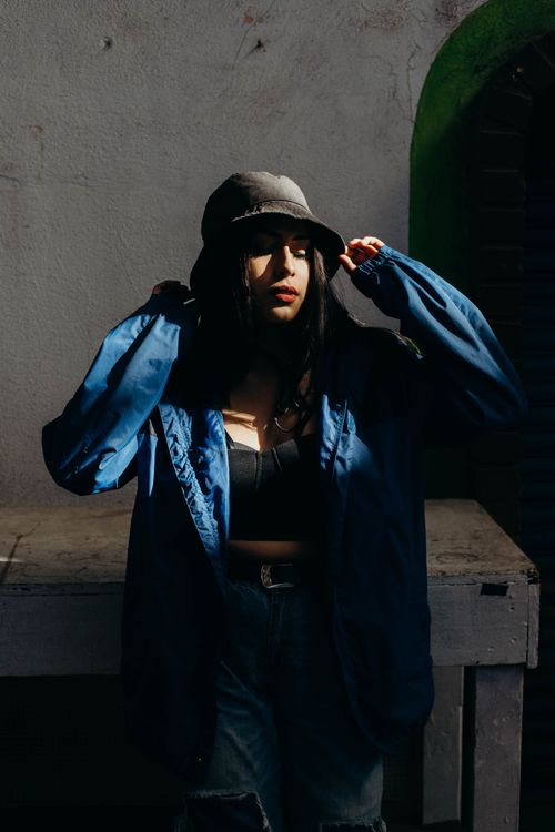 Free Woman in blue jacket and bucket hat showcasing modern urban street fashion. Stock Photo