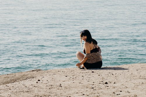 Free A Smiling Woman Sitting on Shore Stock Photo