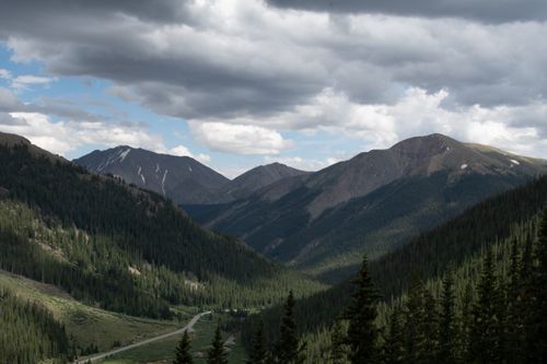 Free Captivating aerial view of a mountain range with a winding road and dense forest. Stock Photo