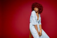 一位红发年轻女子坐在红色背景的凳子上，展现了现代时尚的肖像