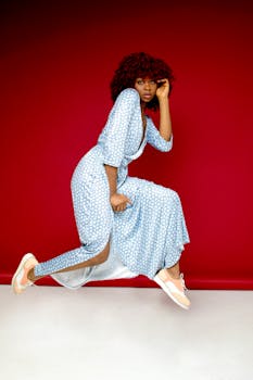 一张充满活力的工作室肖像，描绘了一位身穿时尚连衣裙、以红色背景映衬的年轻女子