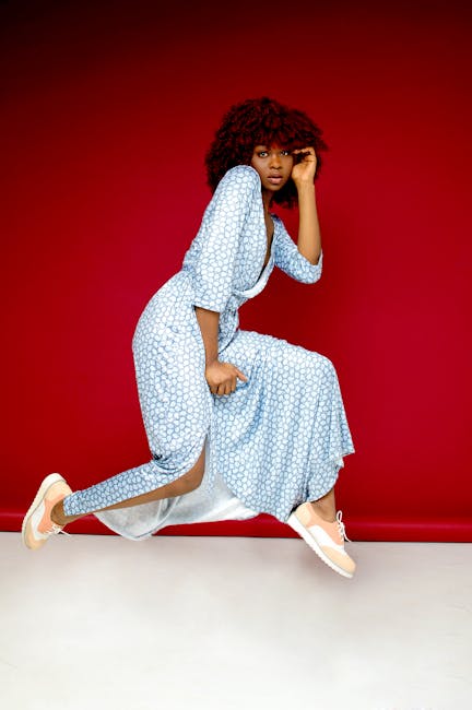 Vibrant studio portrait of a young woman in a stylish dress against a red backdrop.
