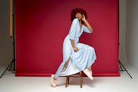 时尚女子在现代室内工作室的红底凳上摆姿势拍摄