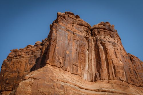 Free Low angle view of towering sandstone cliffs under a bright blue sky, showcasing geological formations. Stock Photo