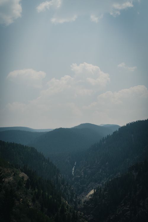 Free Breathtaking view of mountain peaks and dense forest under a cloudy sky, showcasing nature's beauty. Stock Photo