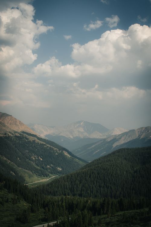 Free Serene mountainous scene with clouds and lush greenery under a hazy sky. Stock Photo