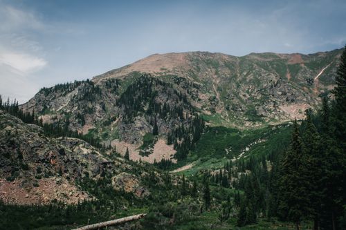 Free A breathtaking view of a lush mountain landscape with rocky slopes and greenery under a clear blue sky. Stock Photo
