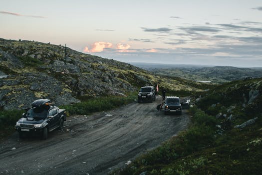 SUVs navigating a rugged mountain dirt road during a remote off-road adventure at dusk.