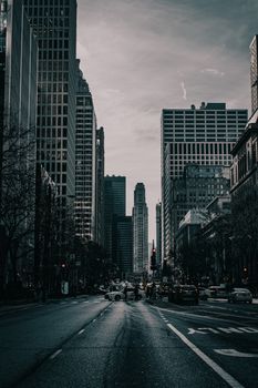 Cityscape with towering skyscrapers and busy street under a moody sky.