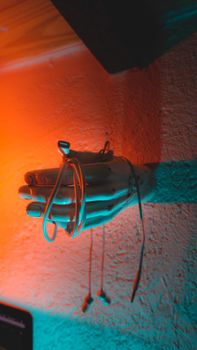 Abstract shot of a hand sculpture holding earphones, illuminated by vibrant neon lighting.