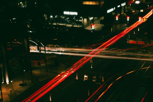 Aerial view of vibrant light trails in an urban city intersection at night.